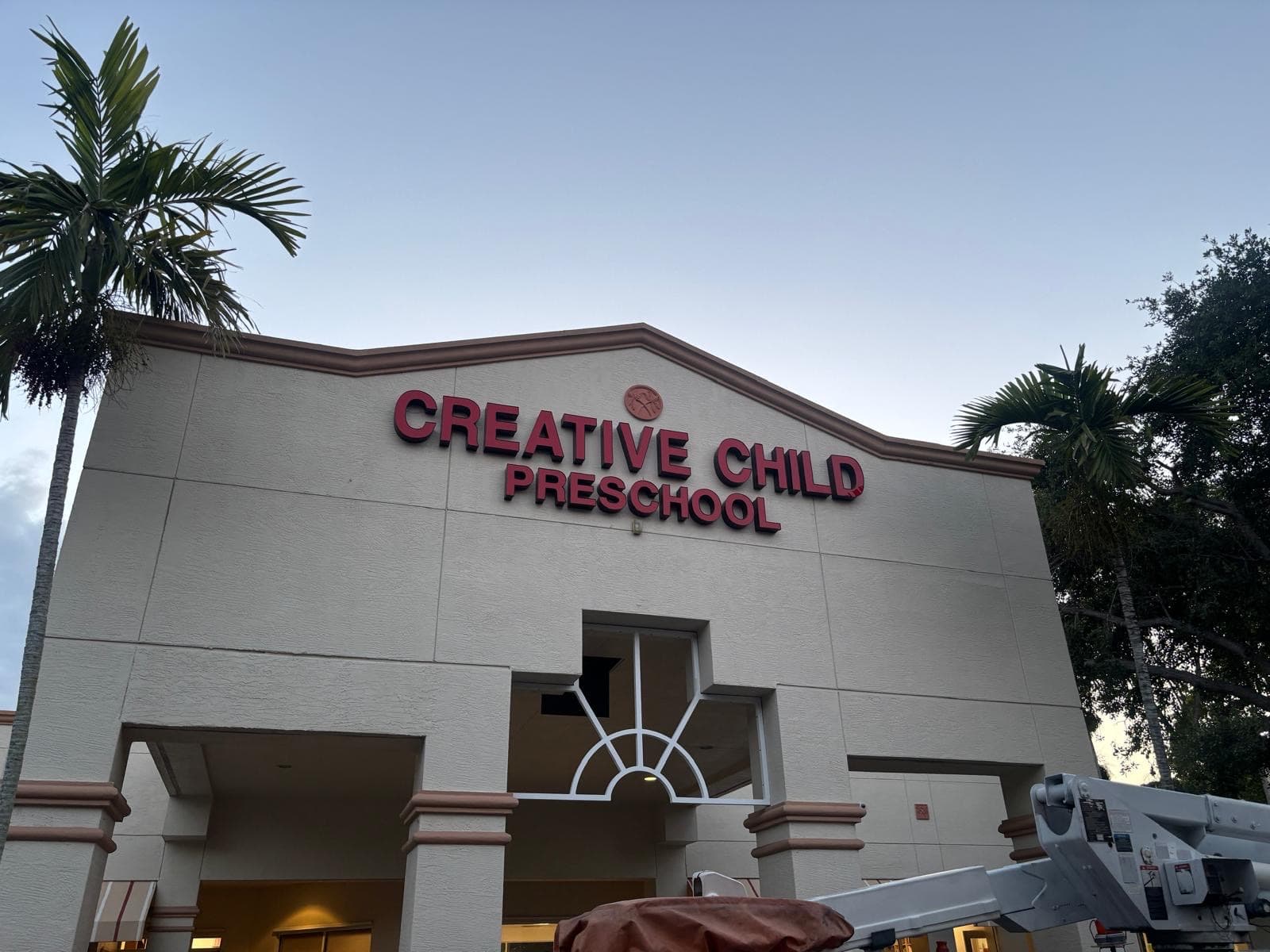 The repaired storefront sign at dusk, every letter back in place