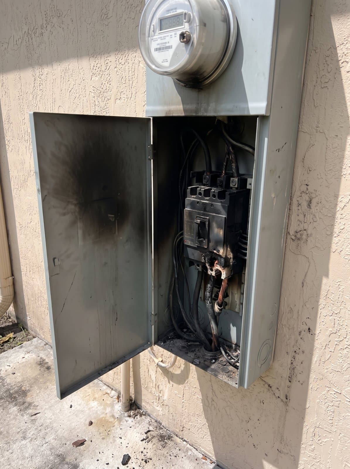 An exterior main disconnect open in daylight, showing a scorched breaker and melted lug from an overheated connection