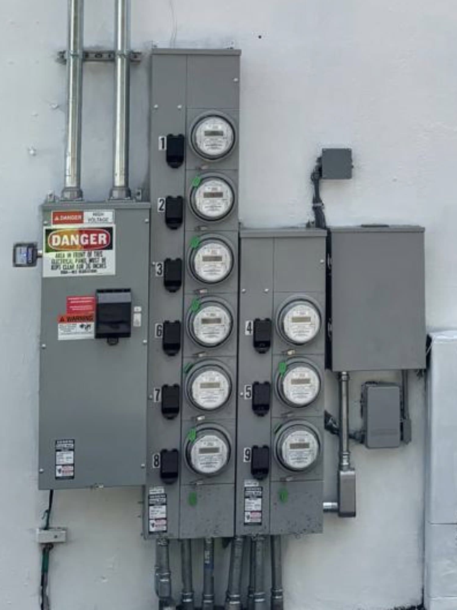 The same wall rebuilt and repainted white, with a new nine-meter bank installed, every meter numbered and back in service