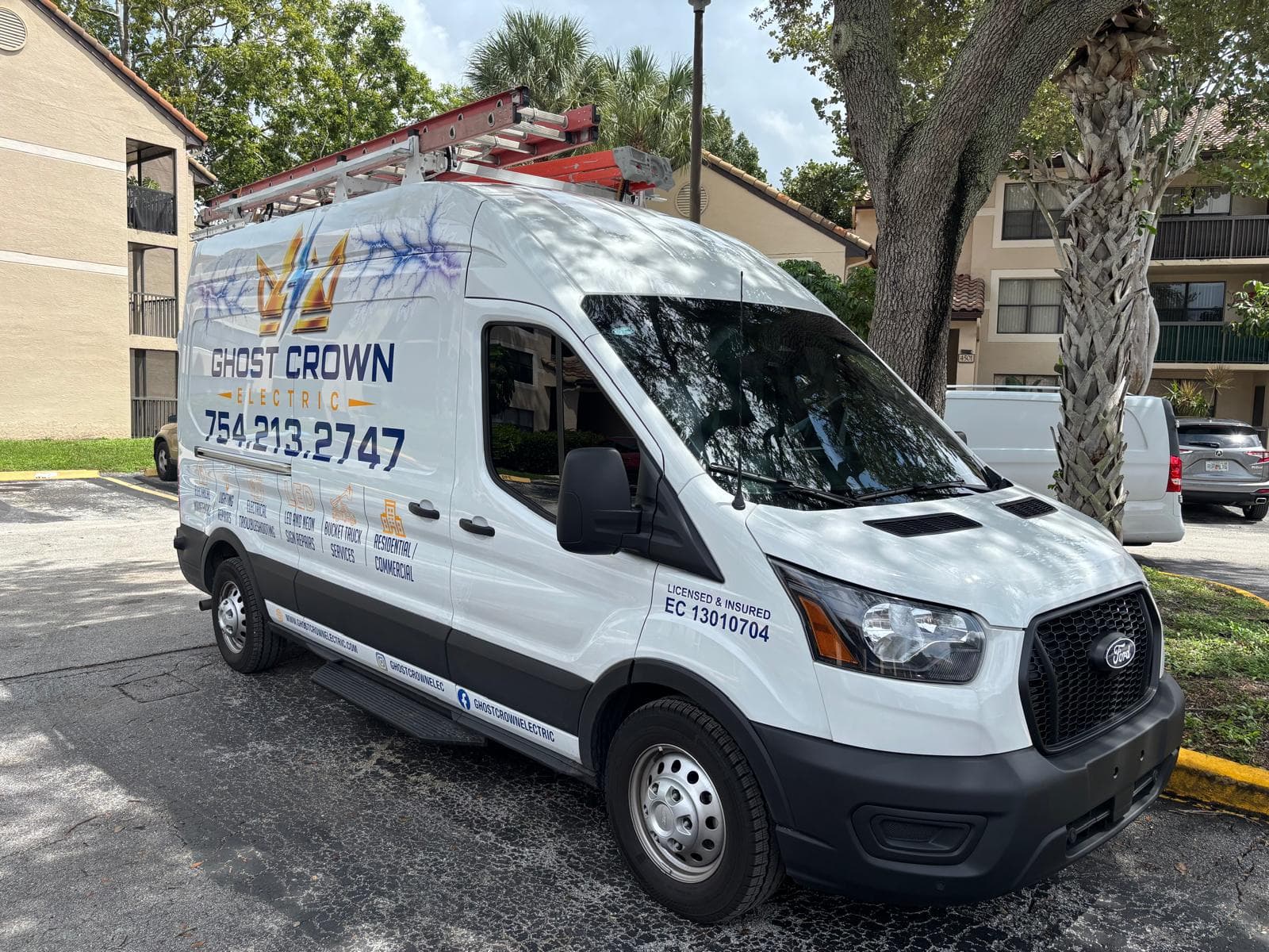 The wrapped Ghost Crown Electric service van parked at a South Florida property on a sunny afternoon